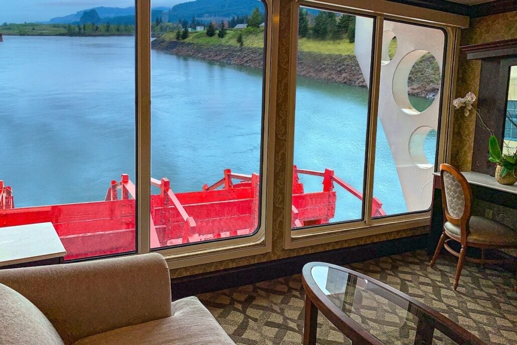 A room on a cruise ship with a view of a river offered by American Queen Voyages.