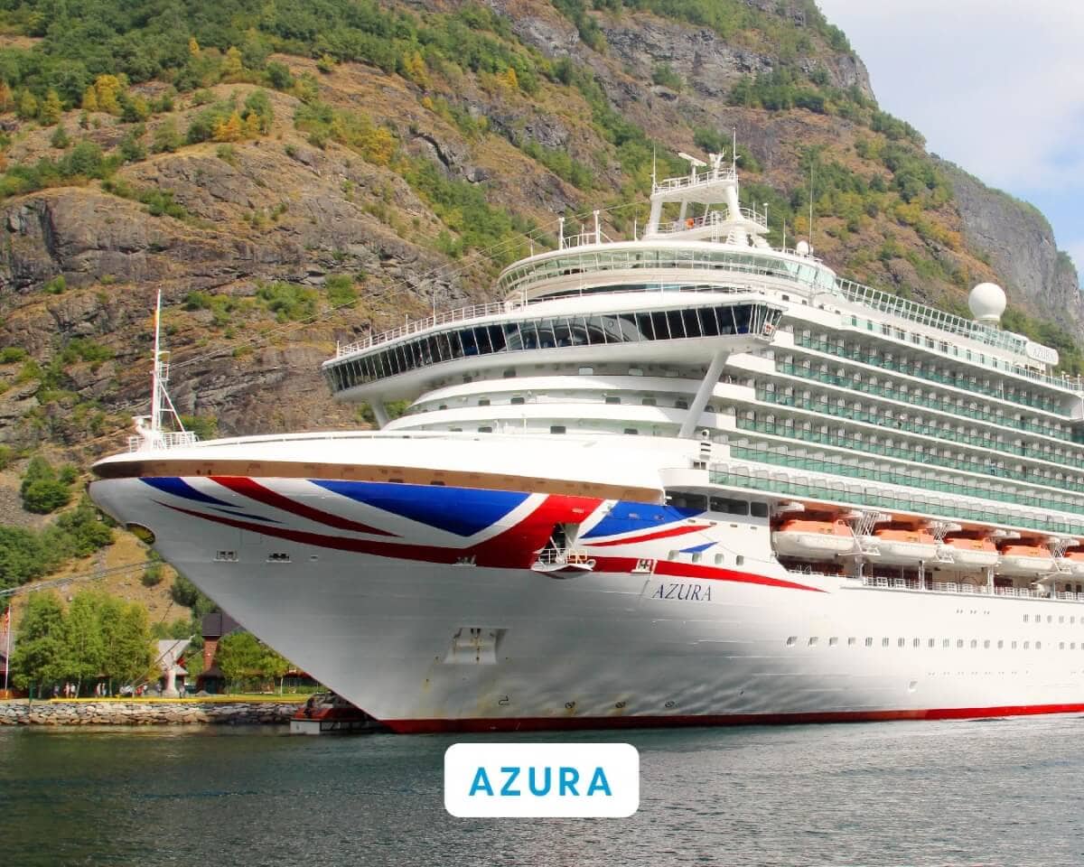 A large P&O cruise ship named Azura, proudly displaying a red, white, and blue painted bow, is docked near a mountainous landscape in the UK.