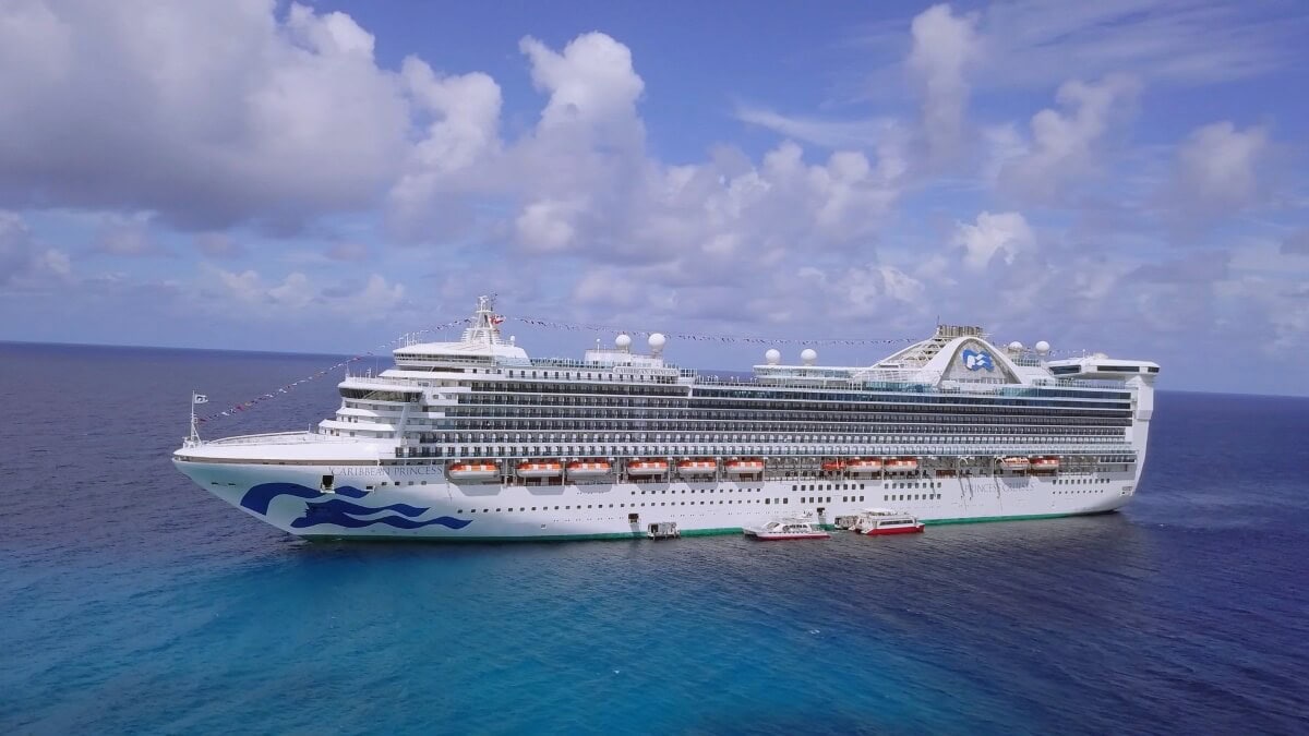 A large white cruise ship floats on a clear blue sea under a partly cloudy sky, heading towards the stunning Eastern Caribbean in 2024.