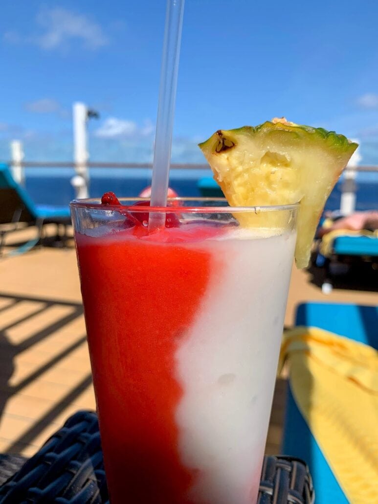 Enjoy a refreshing drink adorned with a pineapple as you relax on Carnival's cruise ship, indulging in their incredible drink package.