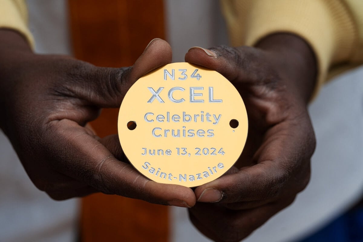 Close-up of hands holding a circular, golden plaque that reads: 