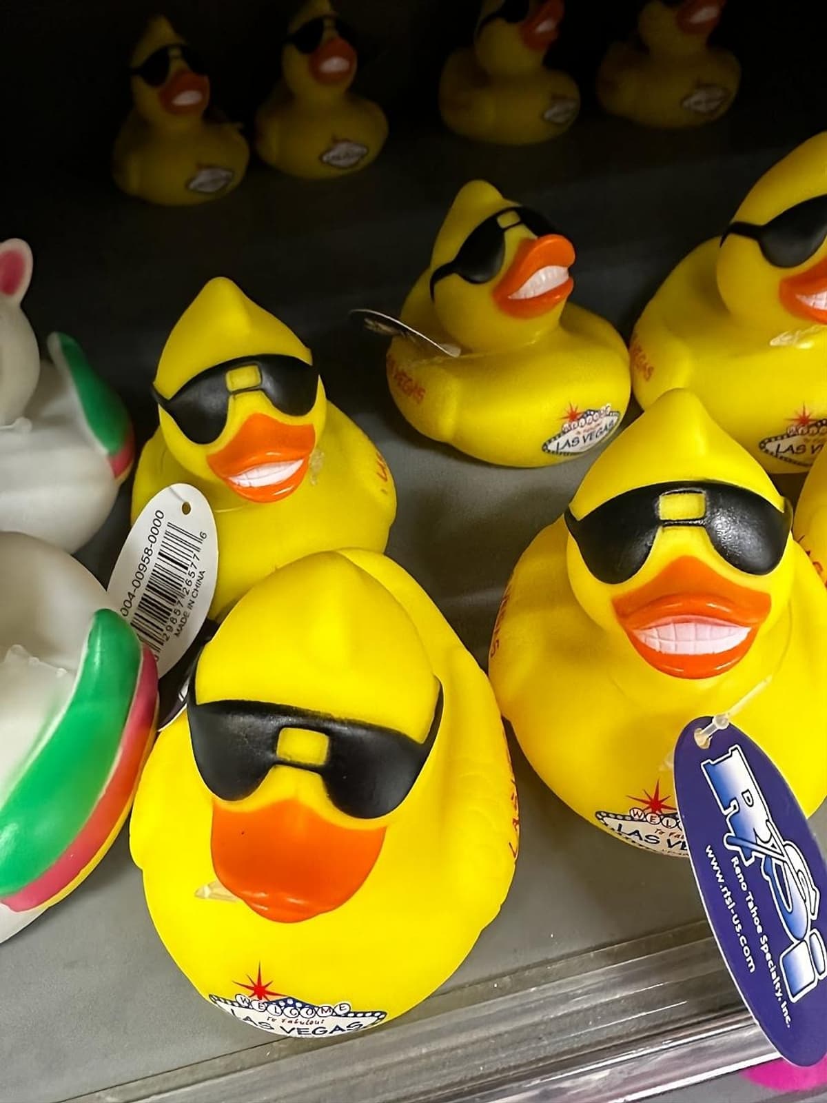 Rubber ducks with sunglasses on display in a store.