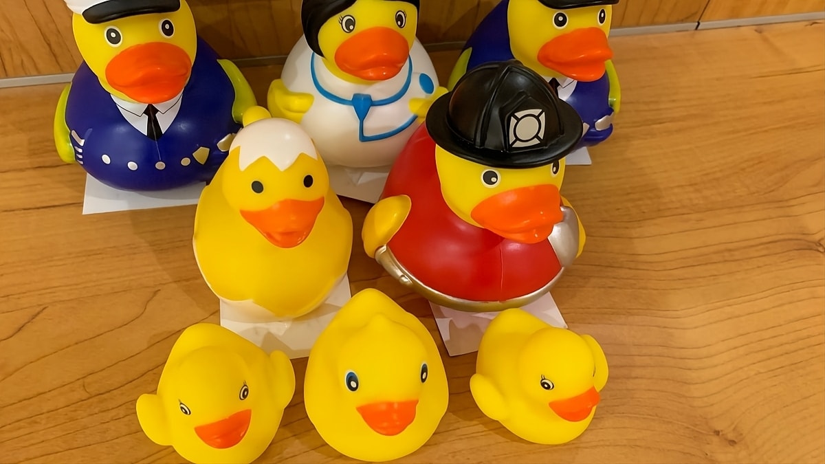 A group of rubber ducks sitting on a wooden floor.