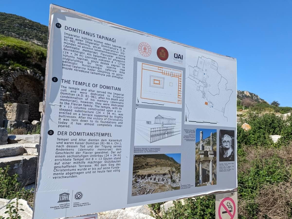 Informational signboard describing the temple of domitian with text in multiple languages, accompanied by illustrations, a map, and located outdoors with vegetation in the background.