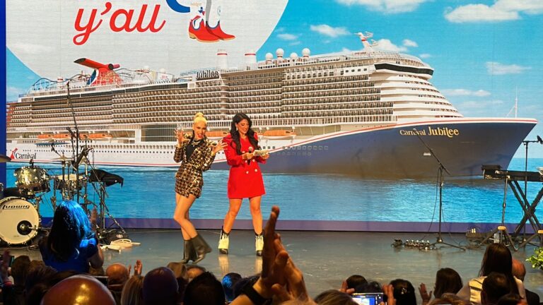 Two women at the VIP Naming Ceremony of Carnival Jubilee on stage in front of a cruise ship.