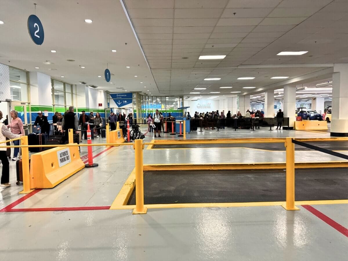 Interior of a vehicle check-in area at a ferry terminal in Alaska with passengers and staff, and marked lanes for car entry.