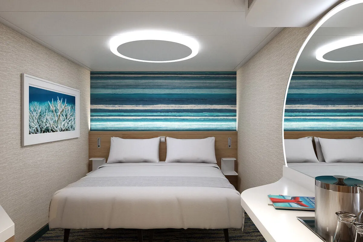 A room on a Carnival cruise with a bed and a mirror.