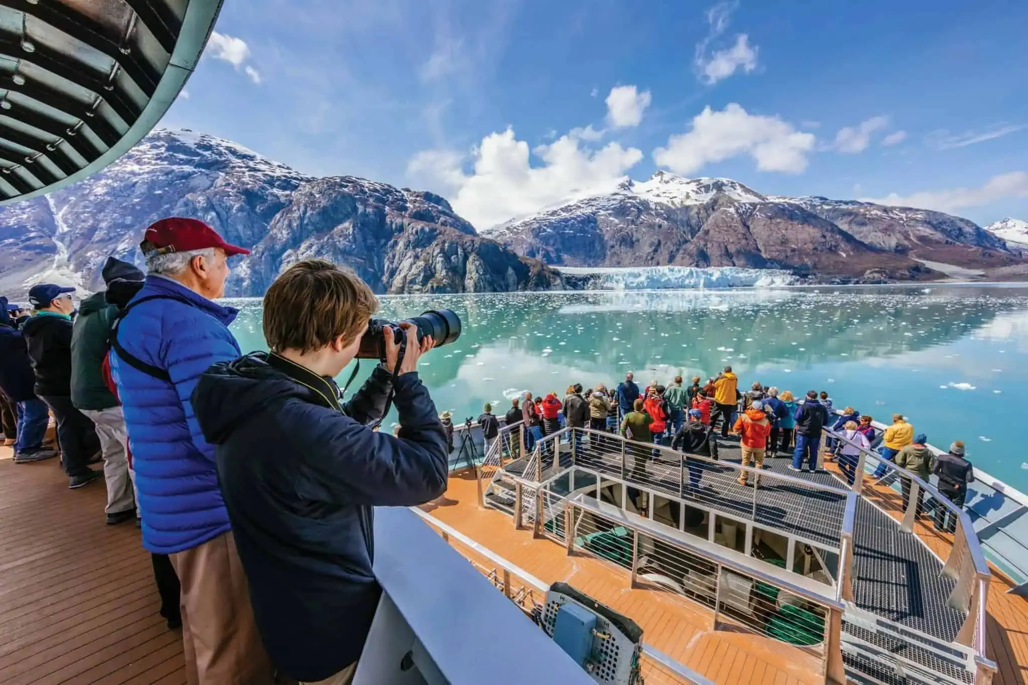 A group of people gazing at a glacier from the deck of their cruise ship.