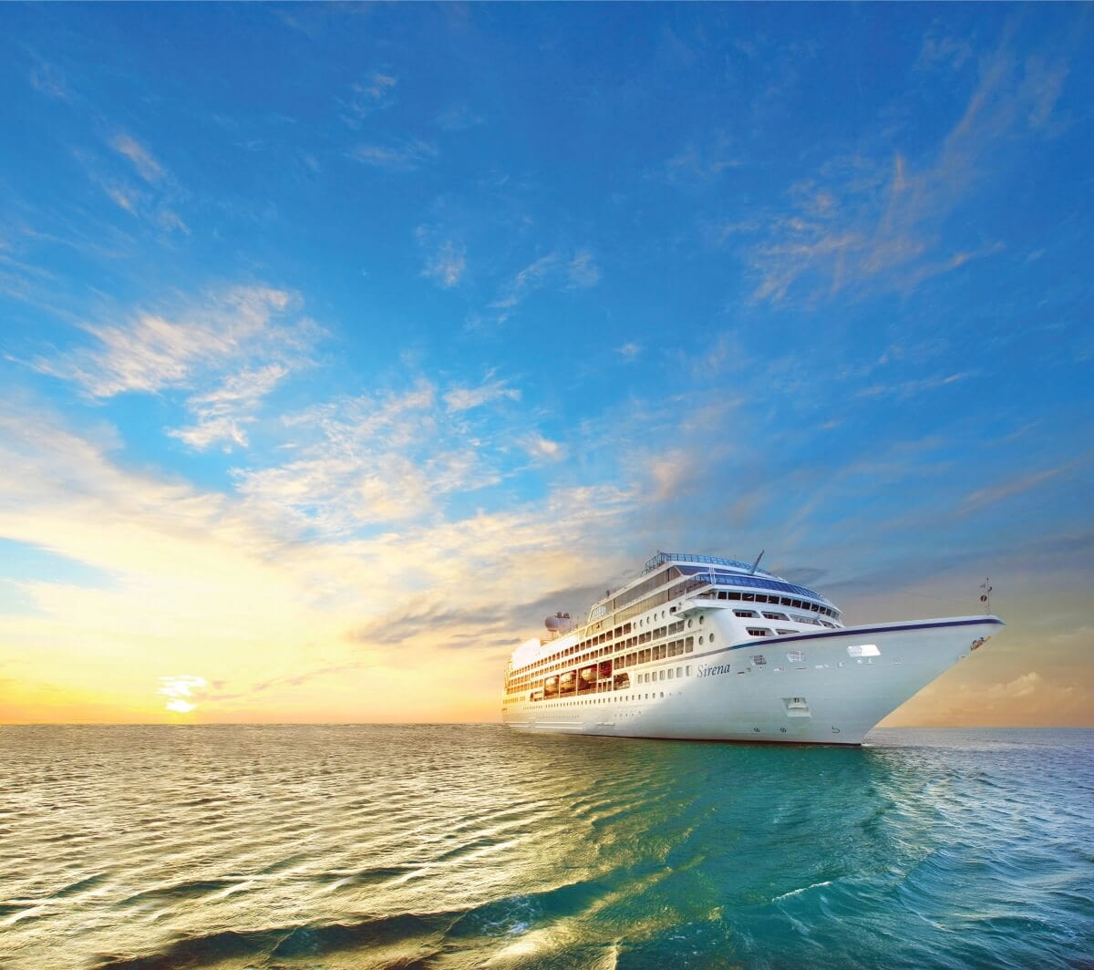 A large Oceania Cruises ship sailing on a calm ocean with a vibrant sunset in the background.