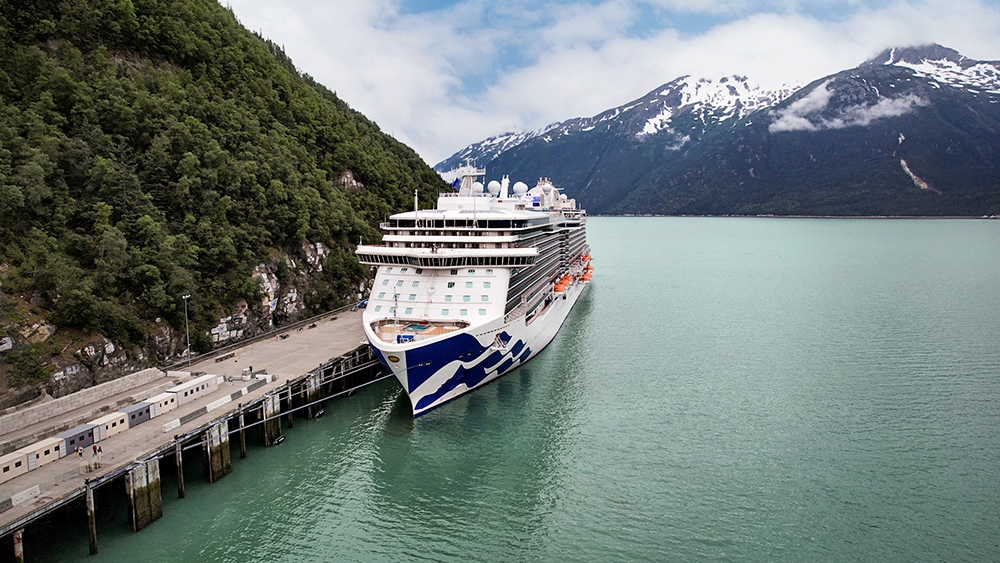 A cruise ship docked in a body of water near mountains in Skagway.