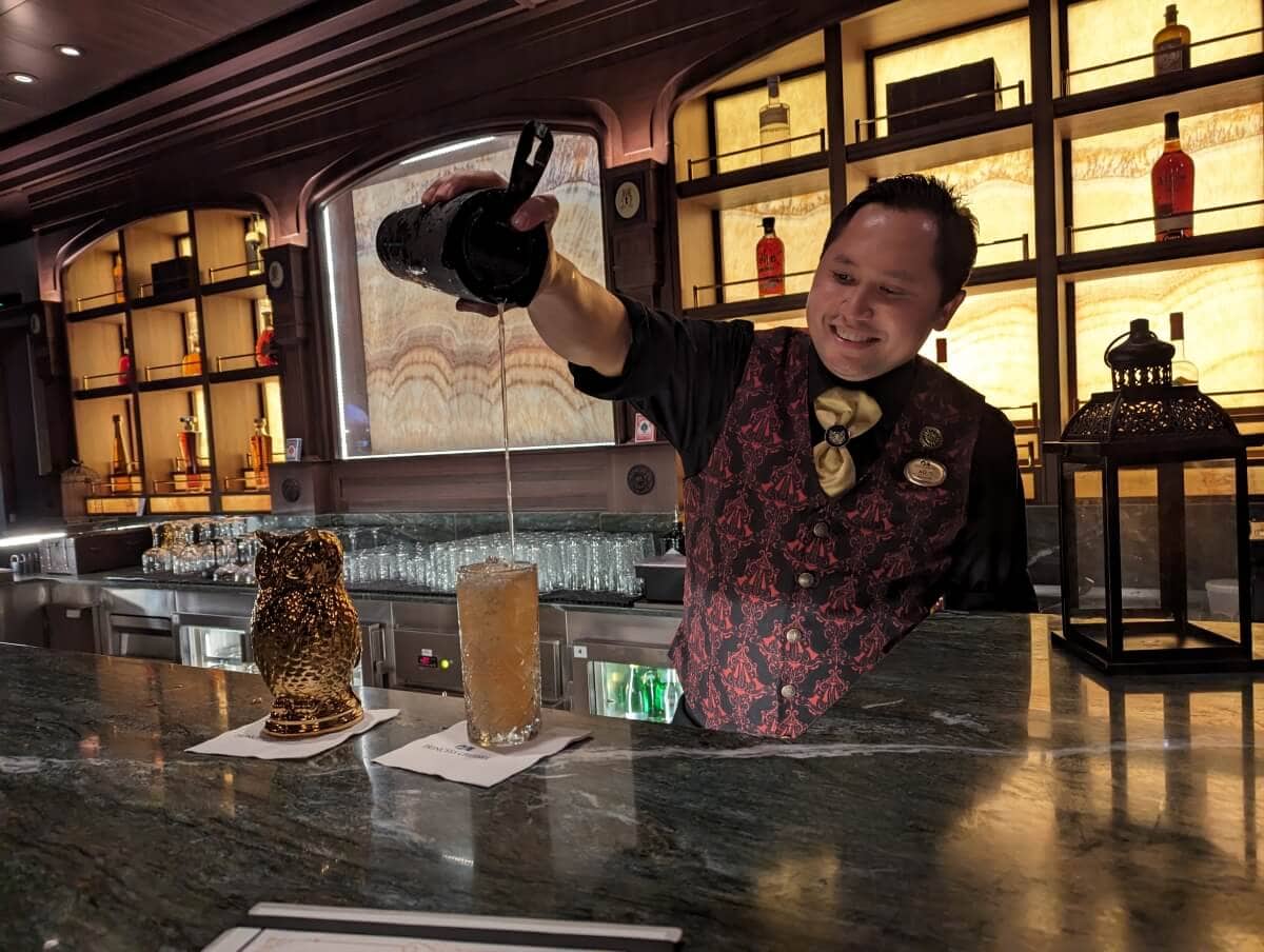 Bartender pouring a drink at a bar counter.