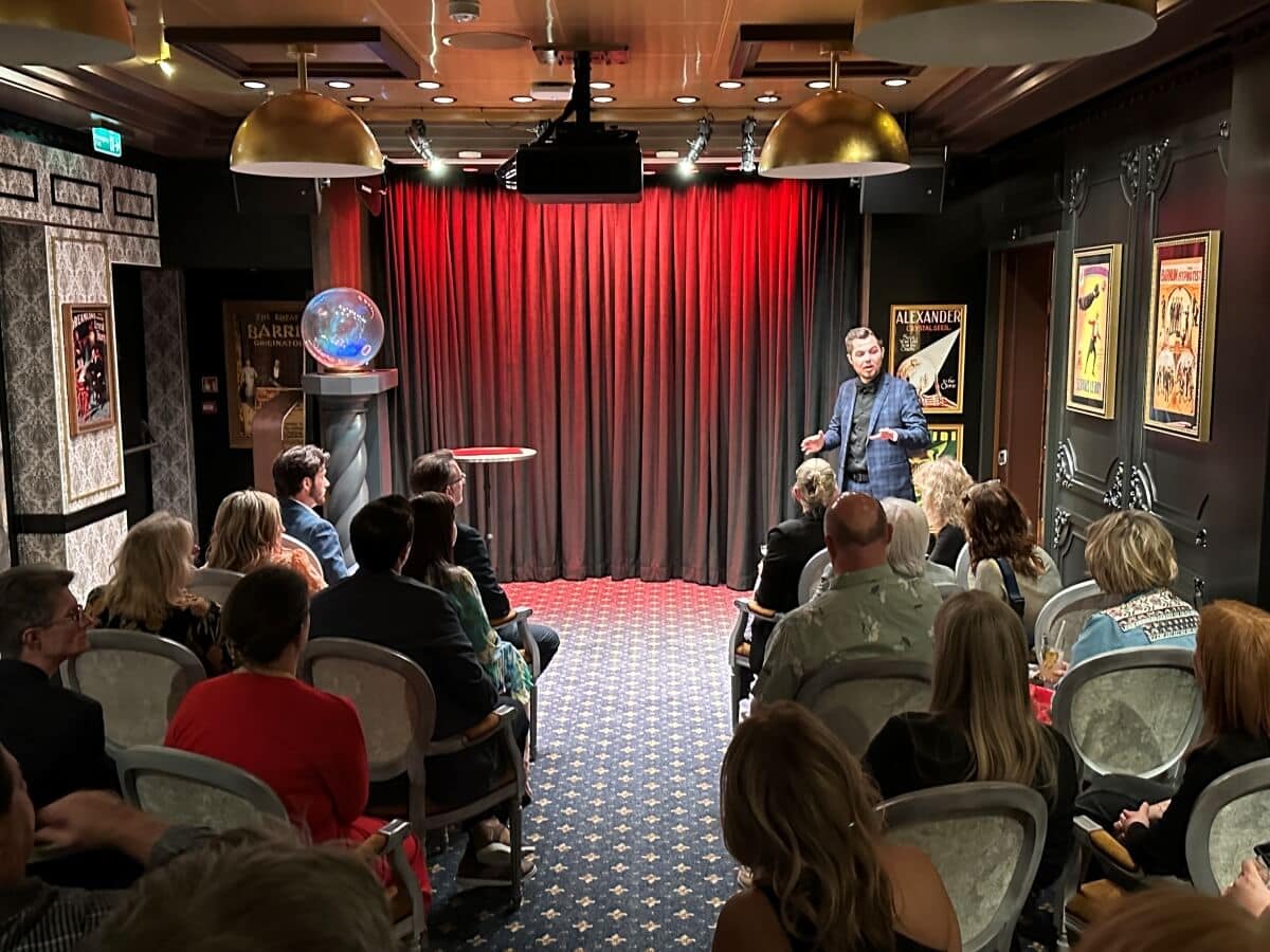 Audience watches a performer on a small stage in an intimate venue.