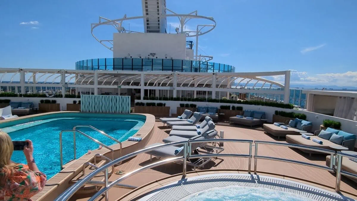 Luxury Sun Princess cruise ship deck with a swimming pool and lounge area under a clear blue sky.