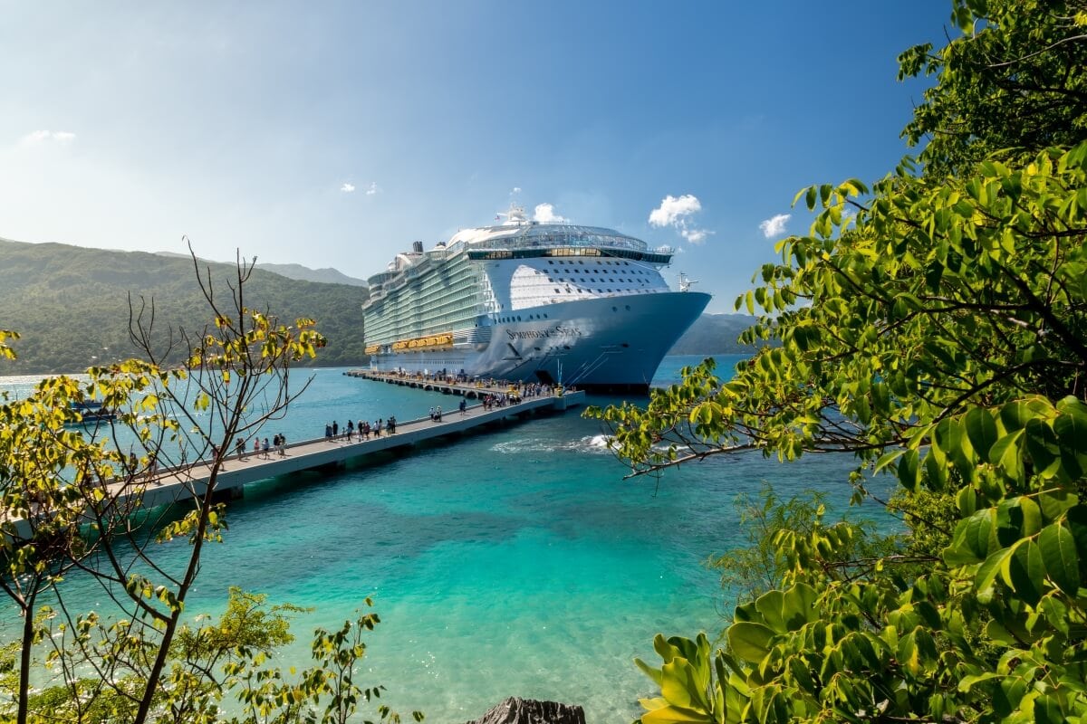 A large cruise ship docked at Labadee's tropical pier with clear blue waters and lush greenery.