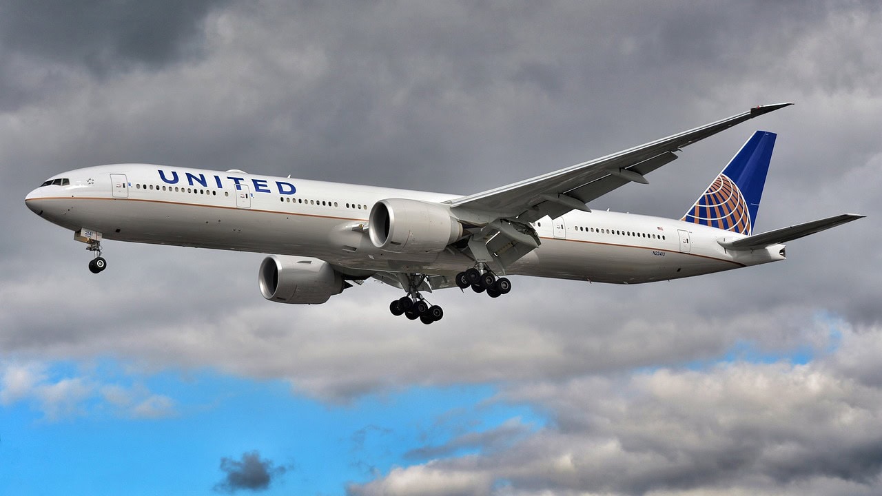 A United Airlines aircraft is in flight against a cloudy sky, following a deep-cleaning procedure to ensure passenger safety.