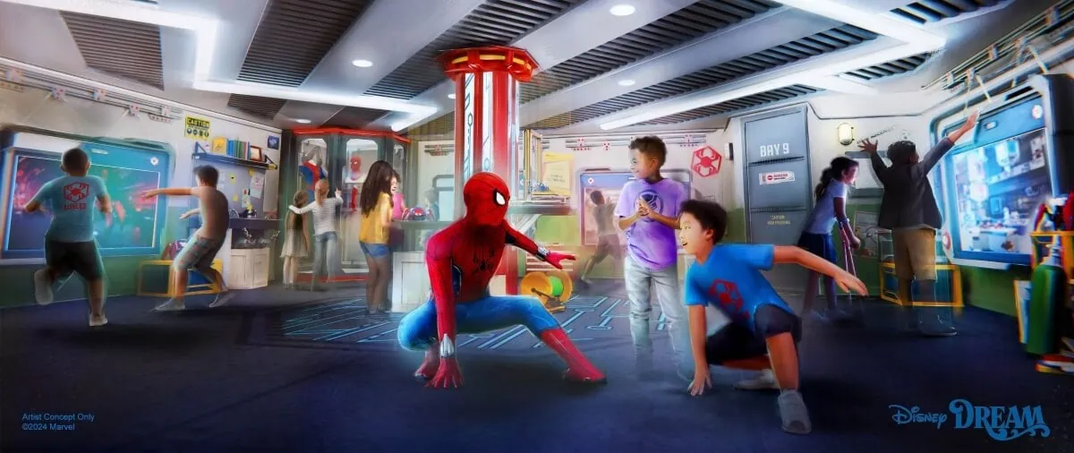 People interacting with various displays and activities in a themed play area featuring a person in a Spider-Man costume, with Disney DREAM text at the bottom.